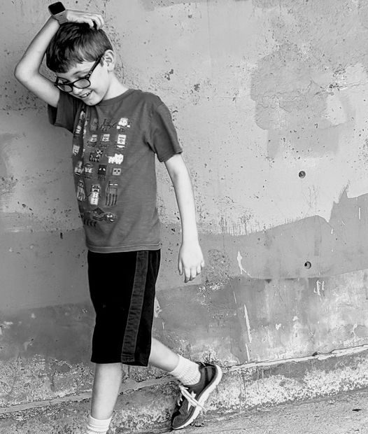 boy leaning against wall, smiling