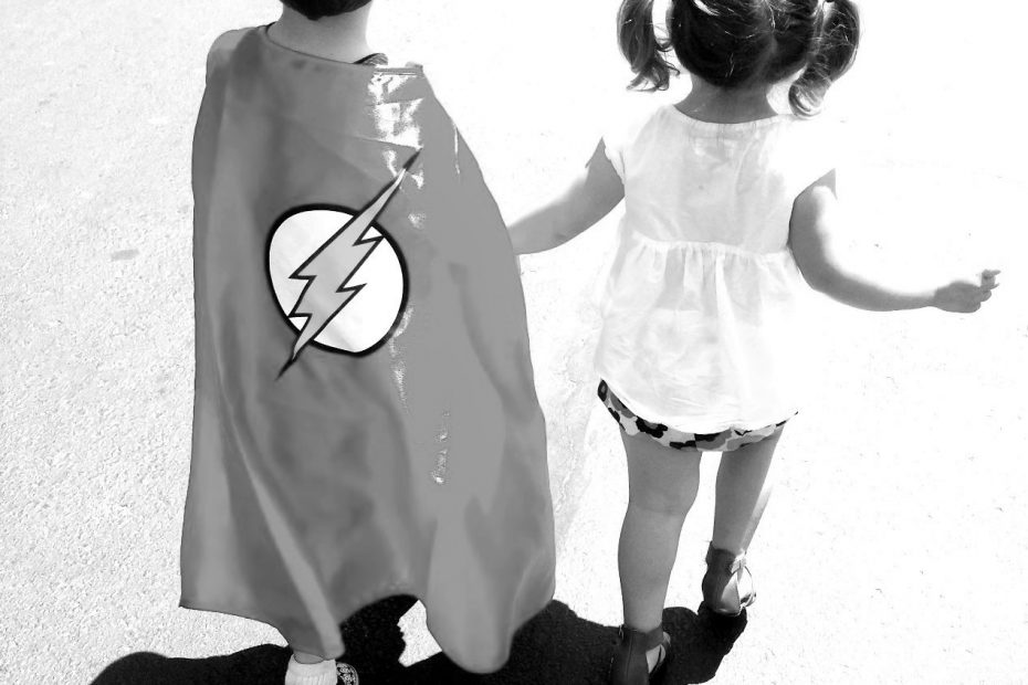 young boy and girl walking holding hands with cape